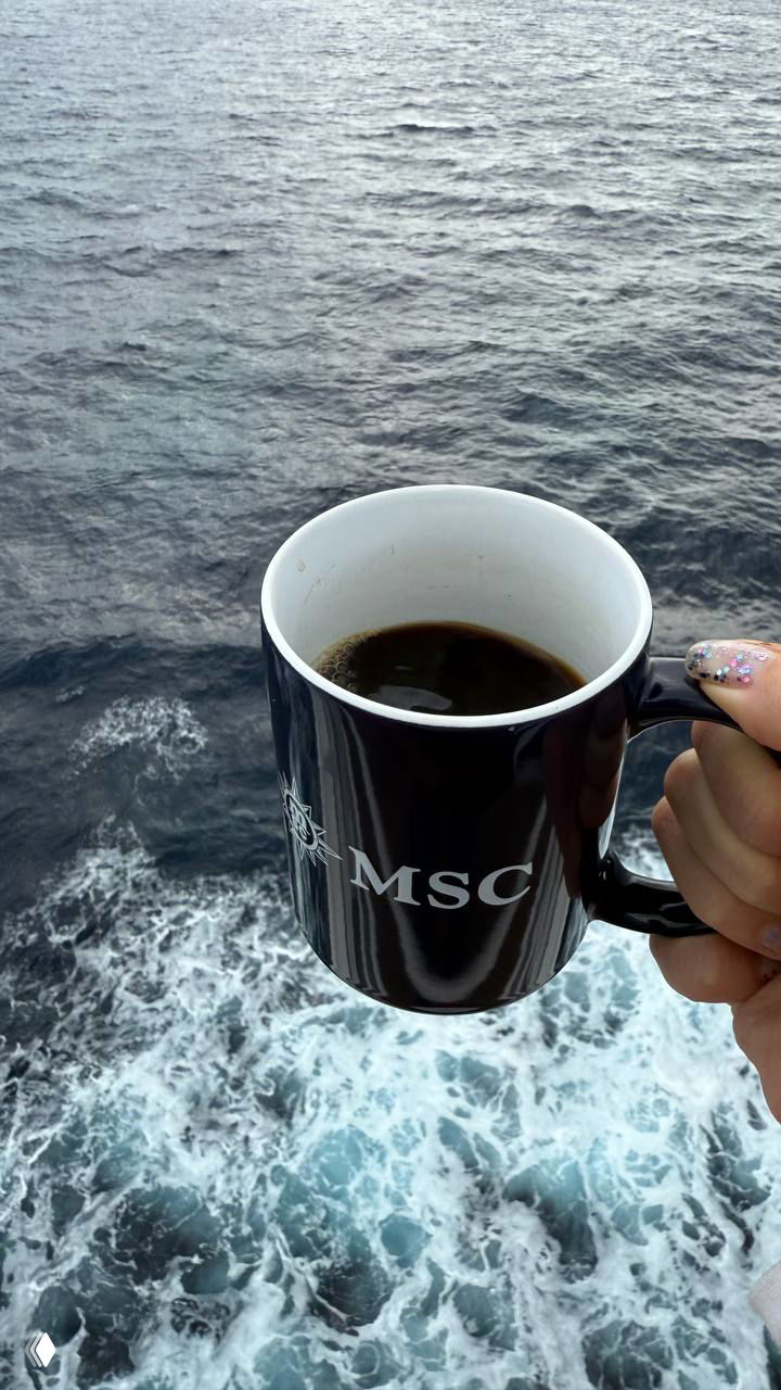 Кружка с логотипом MSC на фоне бушующего моря у борта лайнера — уютный момент с чашкой кофе и видом на волны.