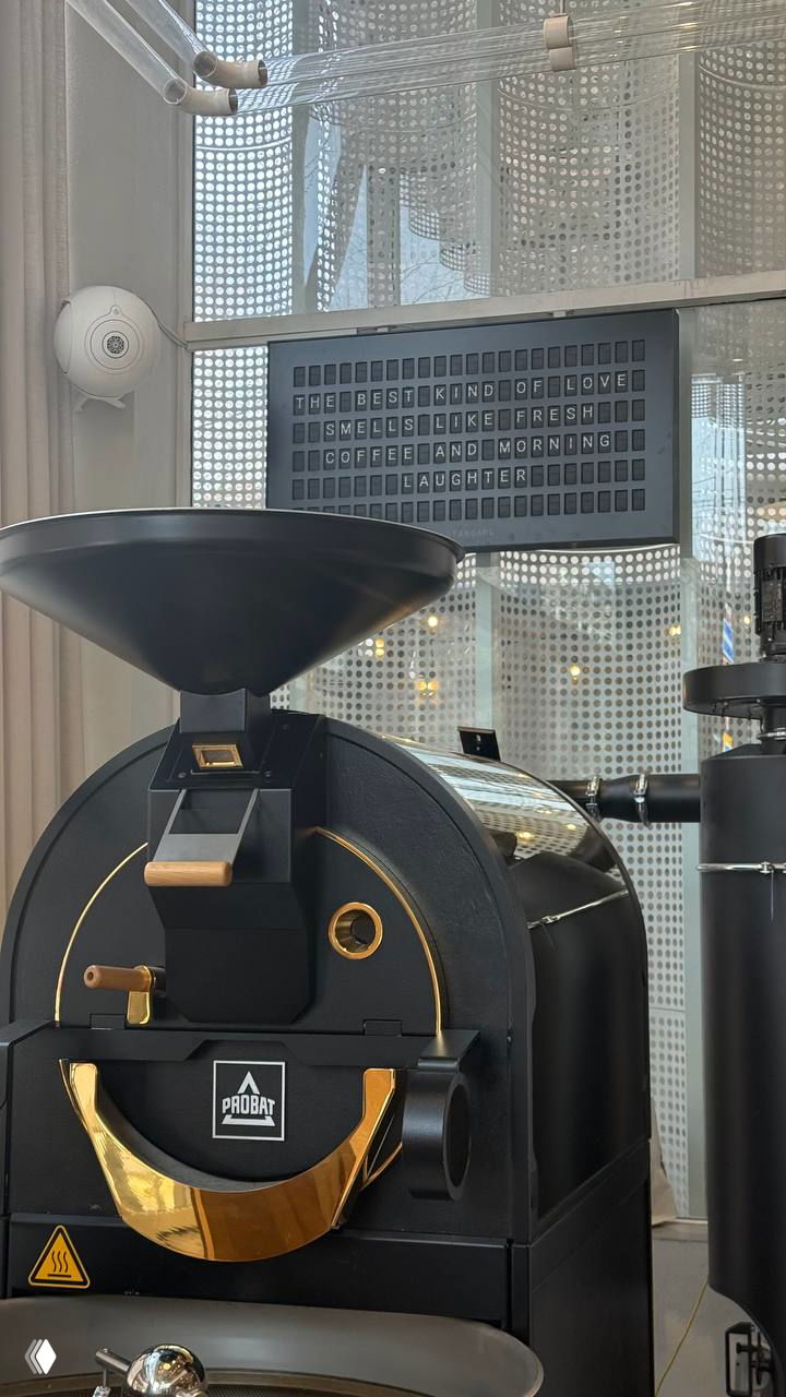 Крупный план обжарочной машины и интерьера кофейни с табличкой на стене — атмосфера кофейного шоу и Specialty coffee в Ереване.