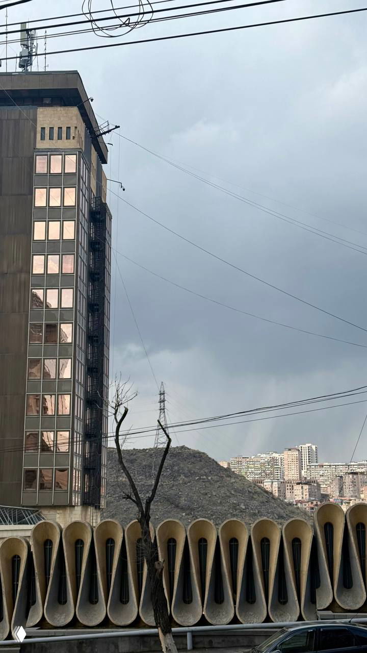 Городской пейзаж Еревана: жилые многоэтажки на холме, провода и архитектурные элементы в переднем плане — урбанистический вид.