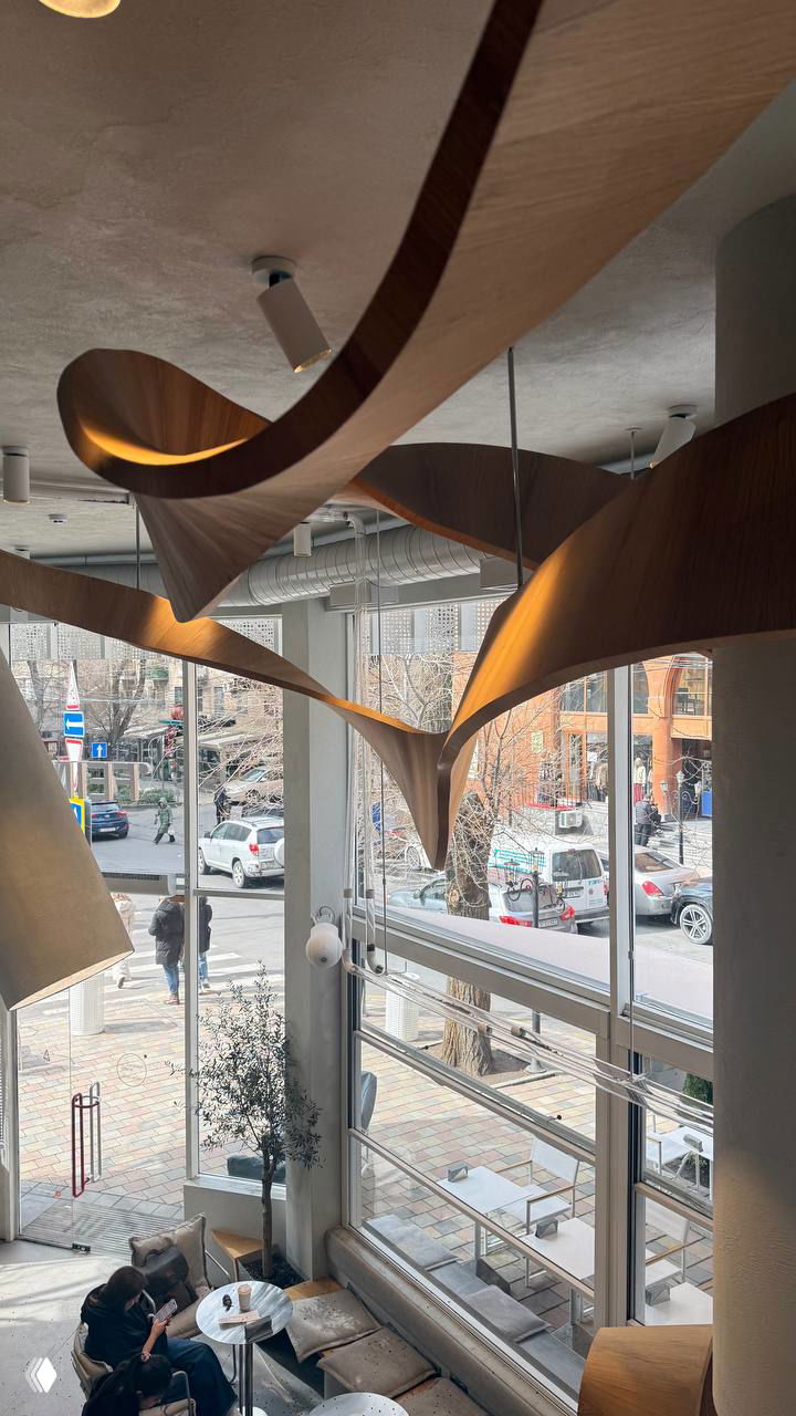 Внутреннее пространство FEIN: светлые панорамные окна, винтовая деревянная лестница и плавные деревянные потолочные конструкции для фото.