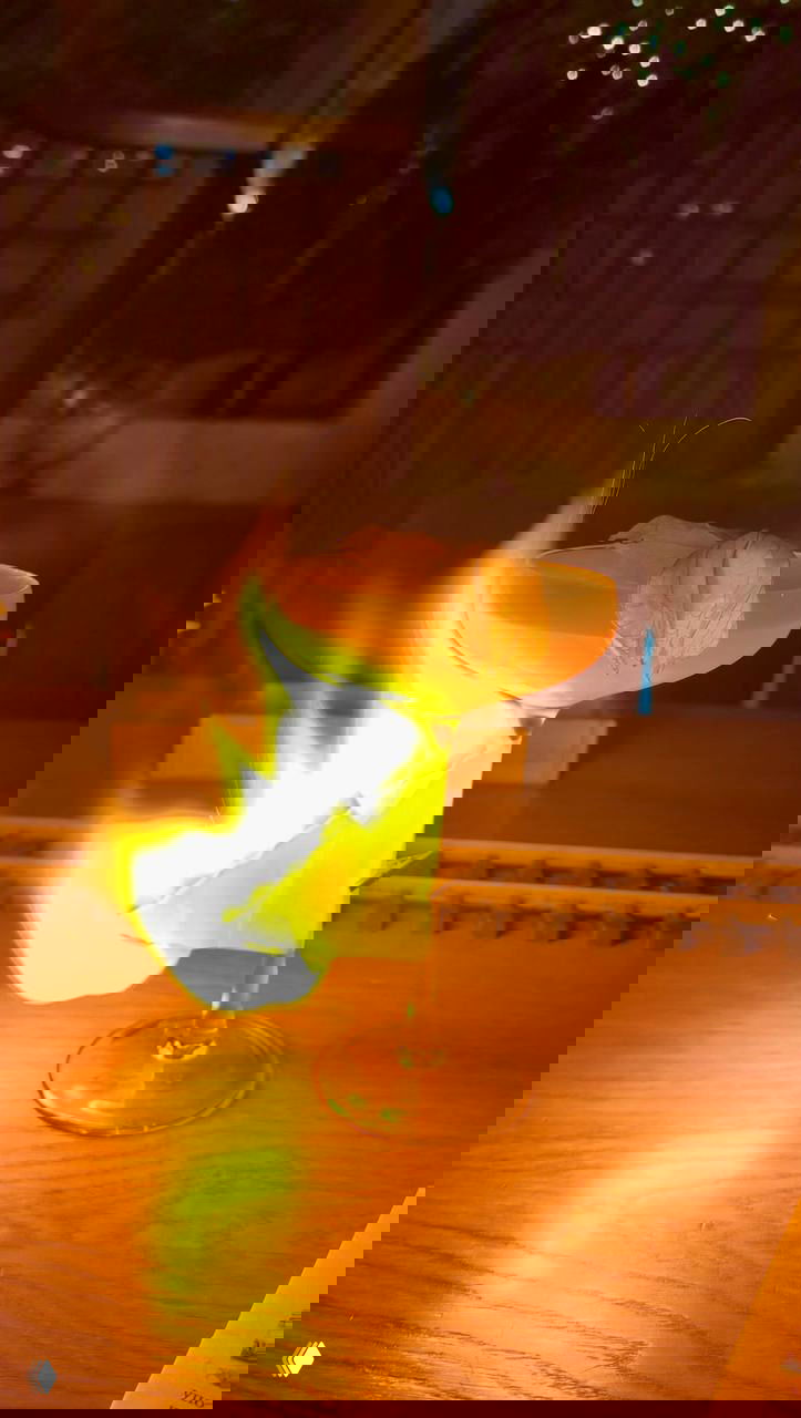 Коктейль или десерт с огненным перфомансом: бокал с пылающим элементом при подаче, тёплое освещение столика и декоративные рельсы рядом.