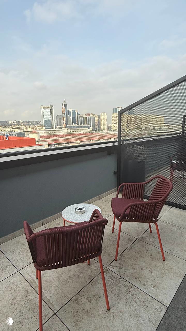 Маленький балкон с двумя креслами и видом на город — приватная терраса стандартного номера CX Napoli Centrale рядом с вокзалом.