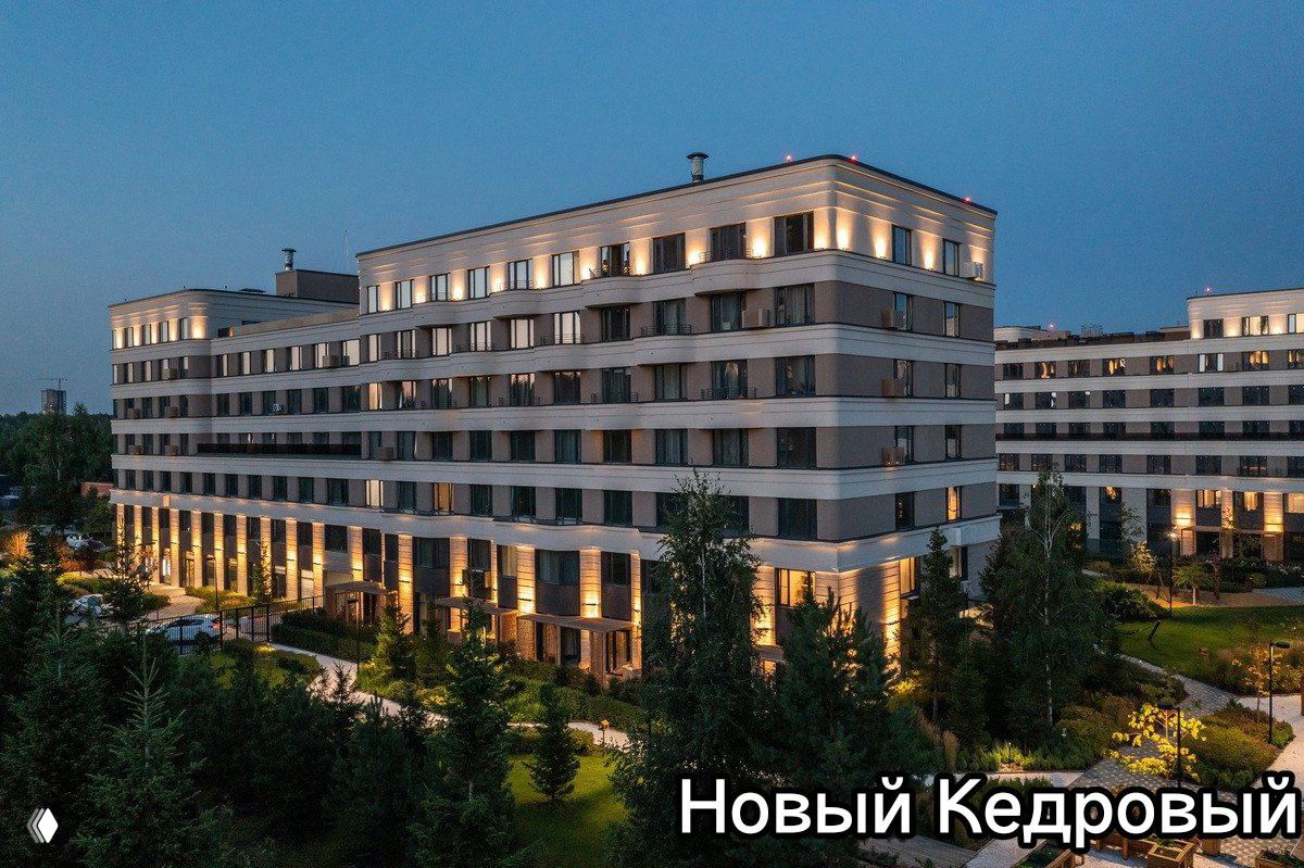 Вечерний кадр ЖК Новый Кедровый: малоэтажные современные корпуса, тёплое фасадное освещение и окружение хвойного бора на территориях комплекса.