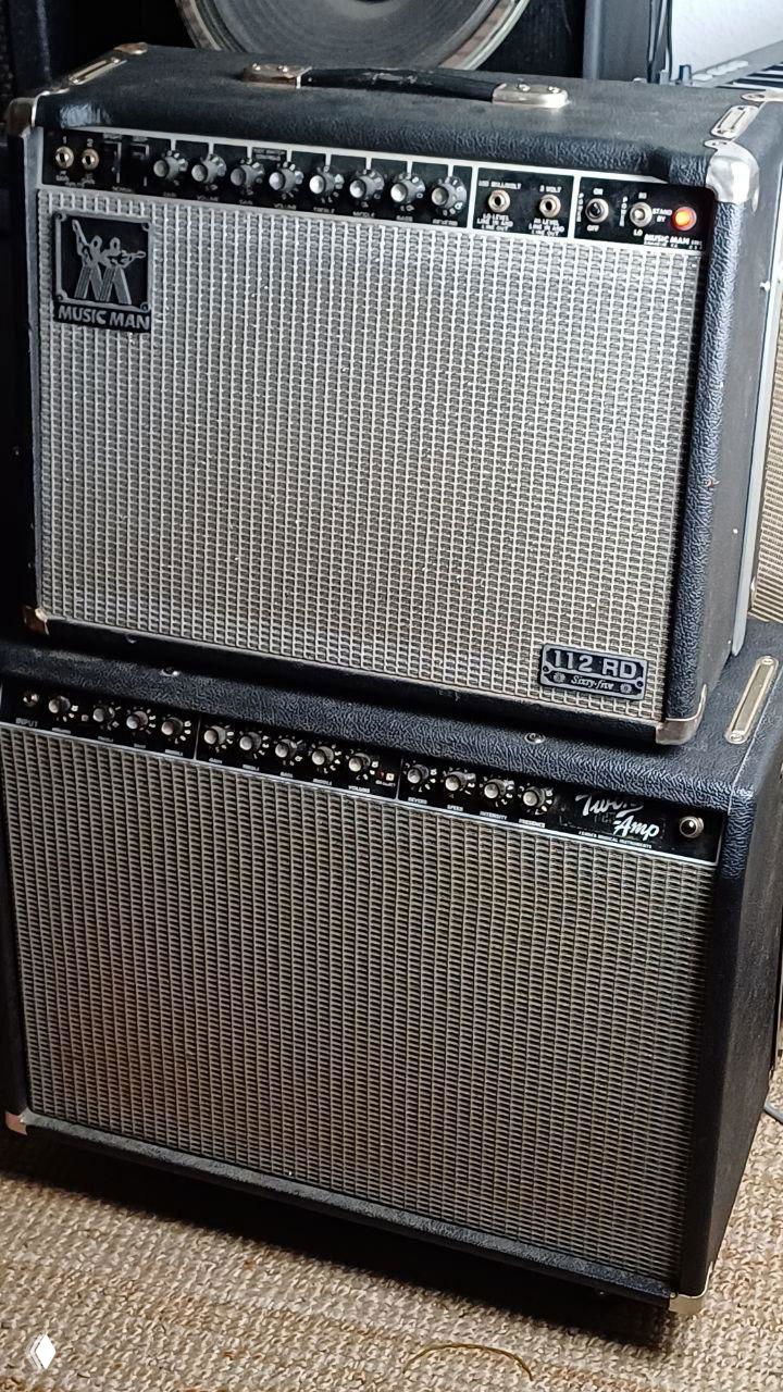 Два комбика, в том числе Music Man сверху, и ещё один кабинет внизу; видны решётки, логотип Music Man и ряд регуляторов на панели.