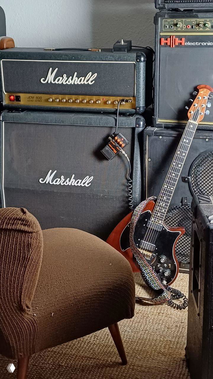 Marshall JCM 800: голова на кабинете, рядом гитара и дополнительные аппараты в углу репетиционной комнаты — атмосферный интерьер музыканта.