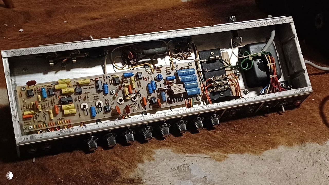 Открытая печатная плата усилителя крупным планом: видны конденсаторы, резисторы, трансформатор и проводка — внутренности лампового устройства.