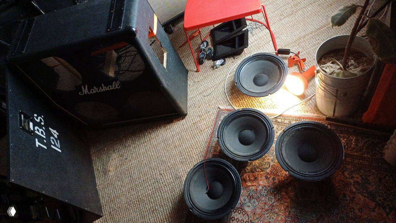 Несколько отдельных динамиков и снятые корпуса на ковре рядом с кабинетом Marshall — подготовка к упаковке или разборке колонок для отправки.