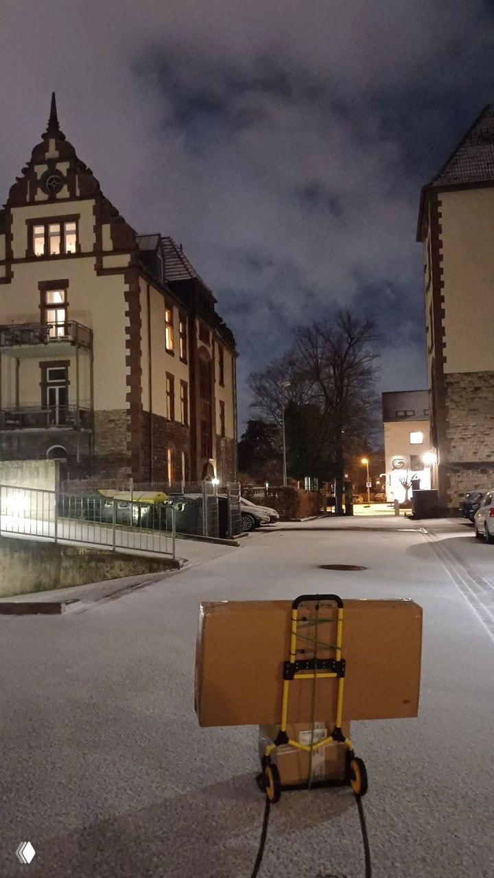 Ночной двор в Европе: тележка с коробкой на первом плане и исторические дома на заднем плане; сцена уличной доставки посылки автором поста.