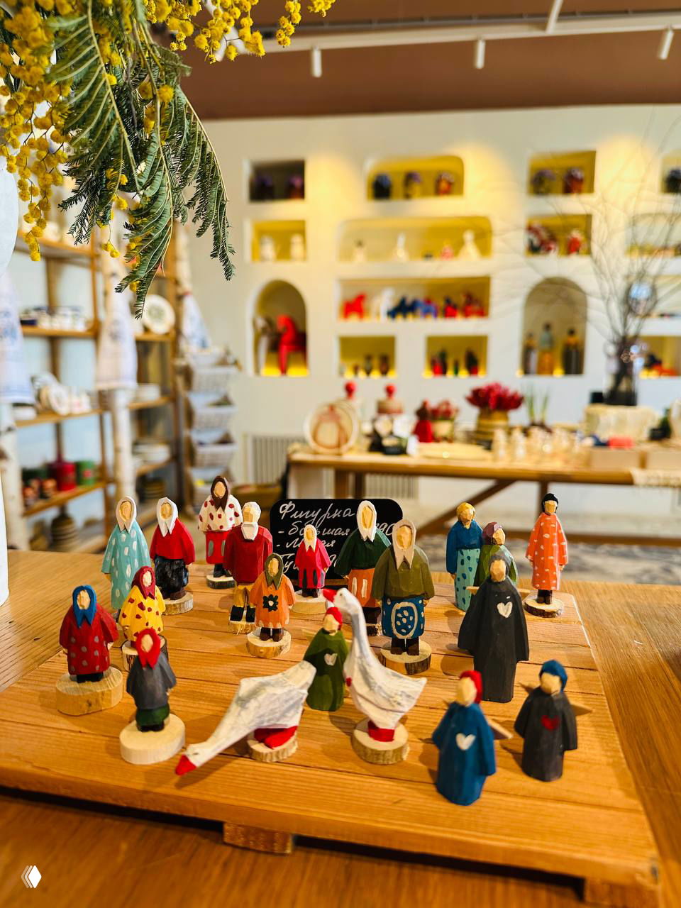Маленькие расписные деревянные фигурки-игрушки и гуси на прилавке сувенирной лавки — тёплый интерьер и детальная рукодельная керамика вокруг.