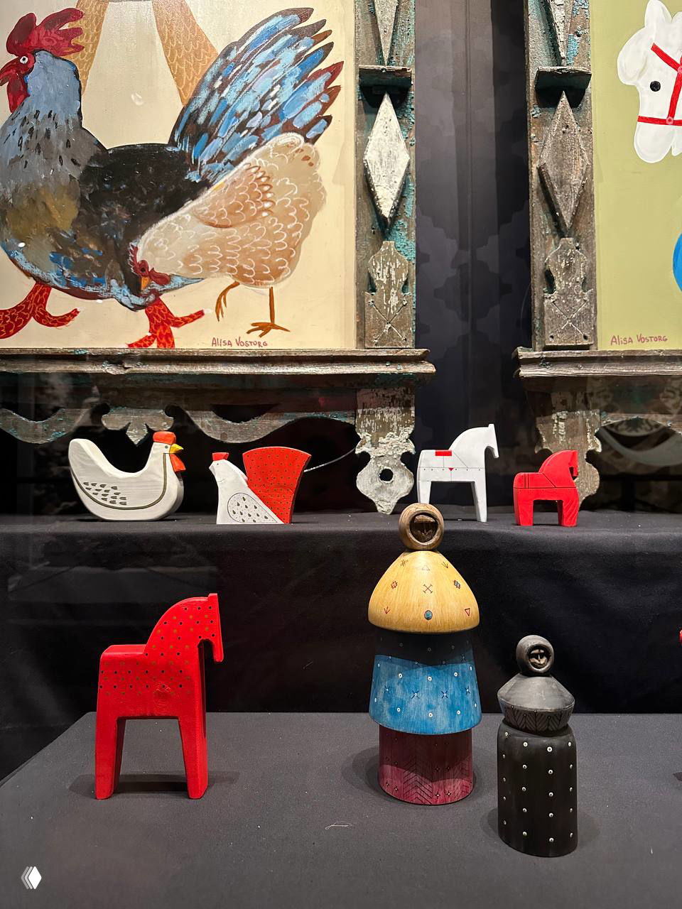 Набор деревянных и раскрашенных игрушечных лошадок и фигурок на уровне просмотра — традиционные мотивы и авторская переработка народного наследия.