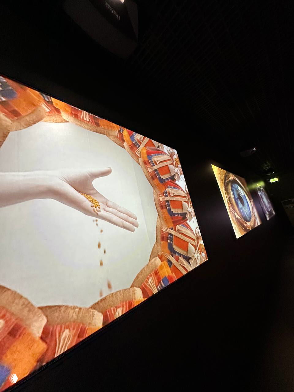 Тёмная галерея с крупными проекциями и мультимедийными экранами — кадр коридора экспозиции с визуальными инсталляциями на стенах.