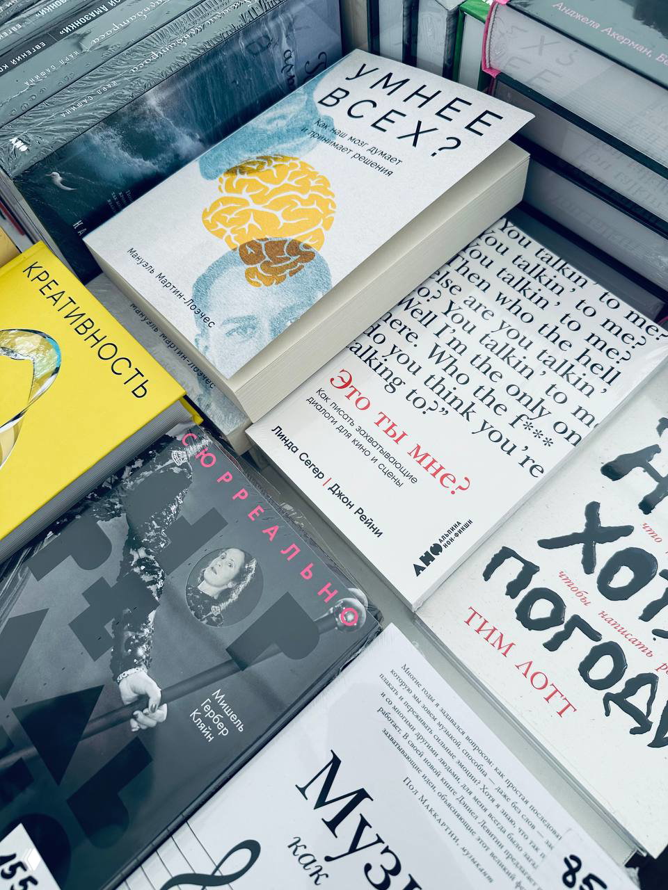 Крупный план стола с книгами на фестивале: обложки разных изданий, заметна книга с иллюстрацией мозга и заголовком на русском языке.