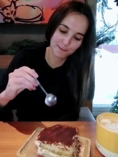 Автор ест десерт в кафе, держит ложку; момент возвращения к обычной еде после снятия ограничений после операции.