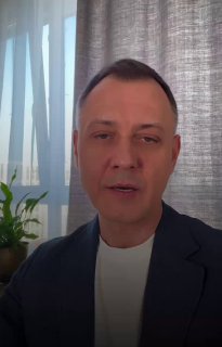 Портрет врача/спикера в деловом костюме на фоне штор и комнатного растения — превью обращения клиники INNOVATICA о медицинских услугах и сервисе.