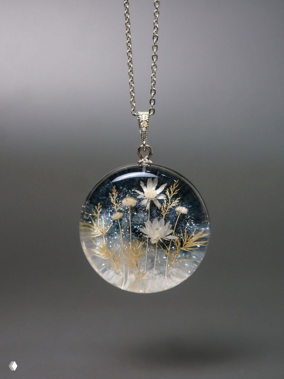 Круглый кулон с белыми мелкими цветами и тонкими золотыми веточками внутри смолы, эффект морозной дымки и лёгких блёсток на фоне.