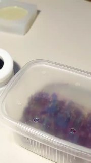 Пластиковый контейнер с застывающей смолой и сухими цветами на рабочем столе рукодельницы — кадр из видео процесса создания композиции