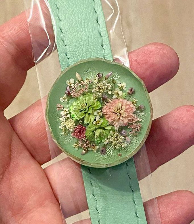 Зелёный круглый медальон на кожаном ремешке с миниатюрной цветочной композицией из сухоцветов под прозрачной смолой.