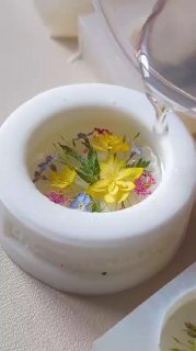 Белая керамическая чашка с яркими жёлтыми и мелкими разноцветными цветами; рядом наливают воду — пример дофаминовой композиции