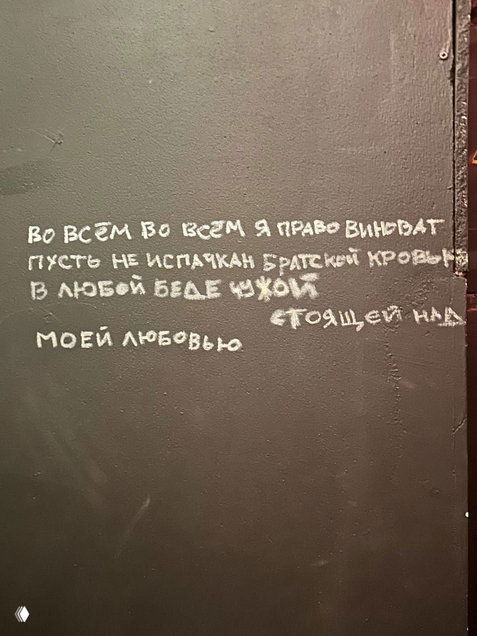 Надпись мелом на чёрной стене внутри заведения: поэтический фрагмент, крупный контрастный шрифт и фактура стены как часть интерьерной эстетики.