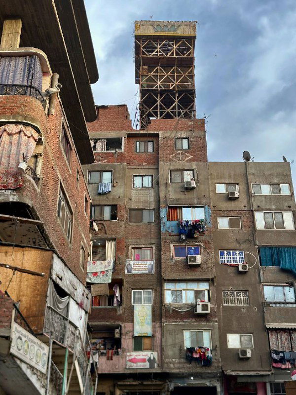 Фасады многоэтажных жилых домов со спутниковыми тарелками и развешанным бельём; городской быт в районе, где живут сборщики мусора.