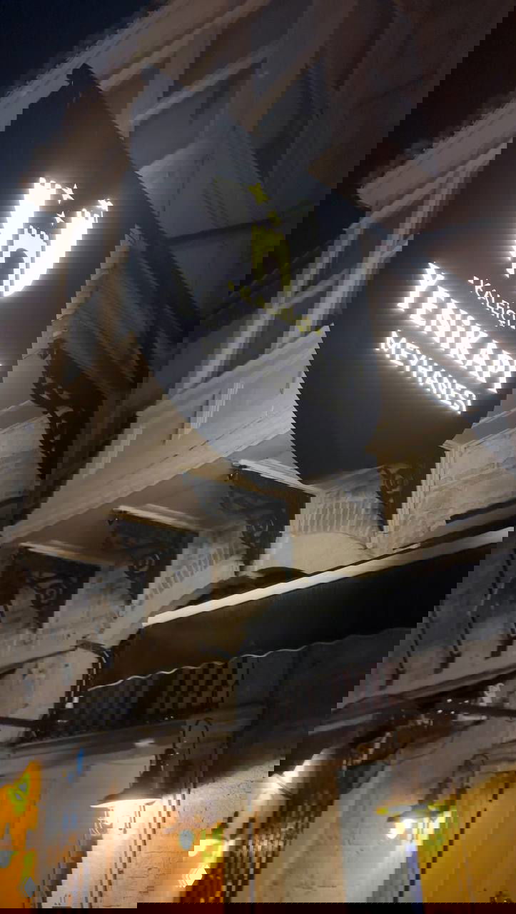 Ночная фотография вывески мейхане с надписью YENIKAPI MEYHANESI на фасаде старого дома, подсвеченные фонари и архитектурные детали.