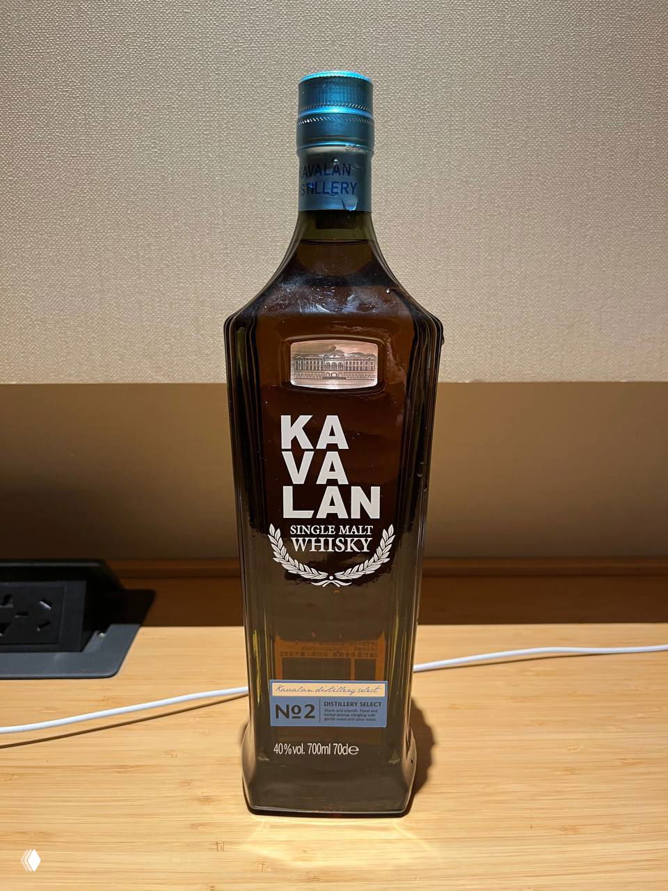 Бутылка виски Kavalan Single Malt на деревянном столе: коричневое стекло, читаемая этикетка Kavalan, бутылка 700 мл на фоне интерьера.