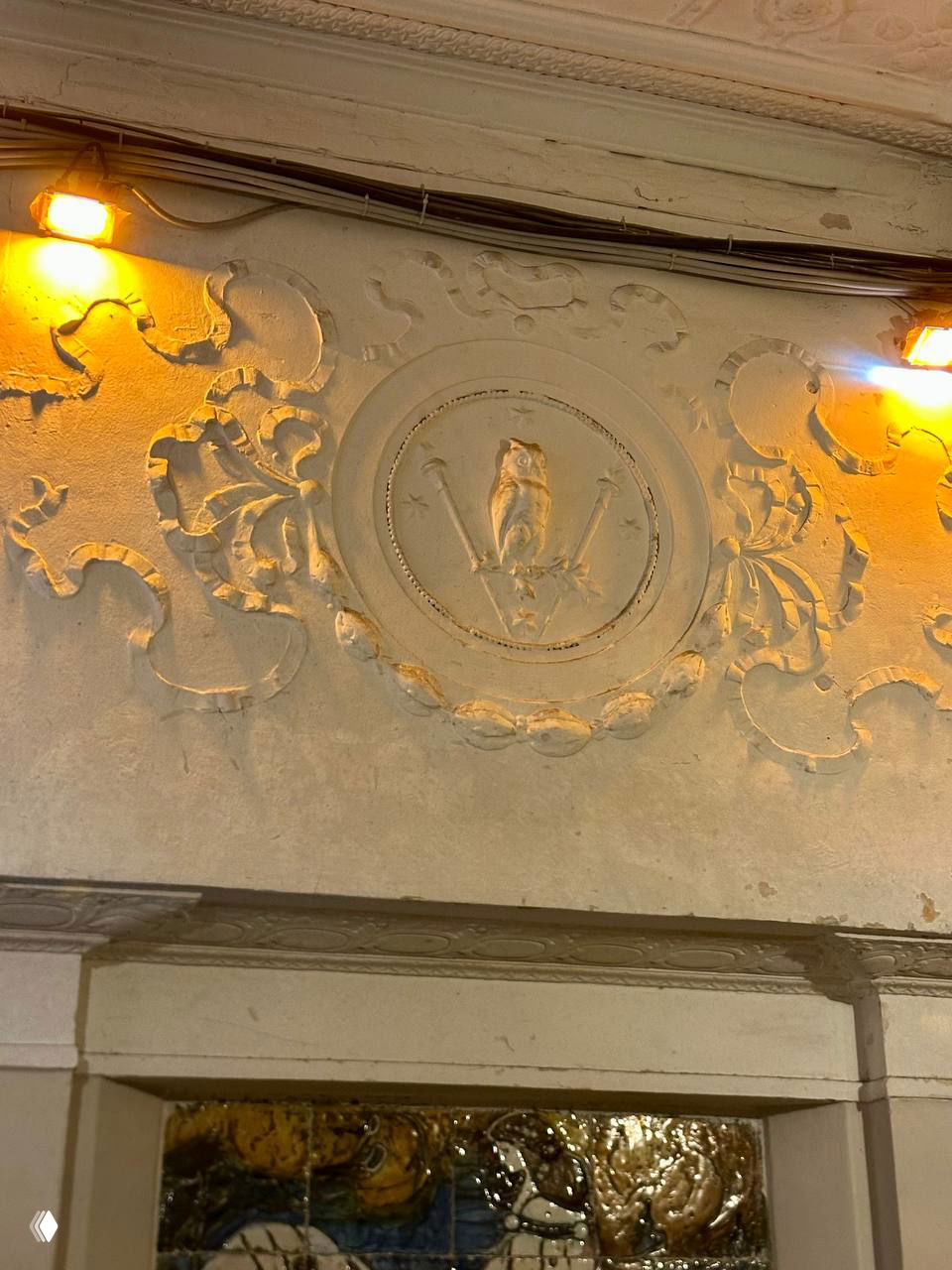 Декоративный лепной фрагмент фасада парадной дома над входом: круглое медальон-изображение с орнаментом и следами времени.