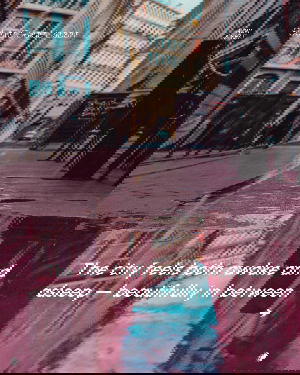 Wet cobbled street in Lisbon with building reflections in a puddle and an emptied urban scene that evokes the cities feeling both awake and asleep.