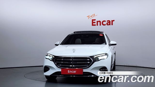 Фронтальный вид Mercedes‑Benz E220d 2024 в студии Encar, видна фасадная часть, красная табличка Encar на бампере.