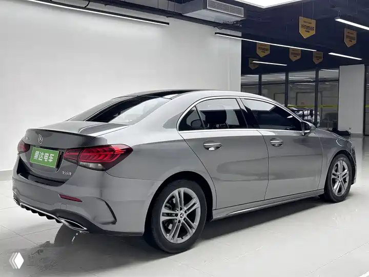 Серый Mercedes‑Benz A‑Class A 180 L Sport Sedan 2022 — вид сзади и сбоку в выставочном боксе; видны задние фонари и профиль кузова.