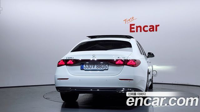 Вид сзади Mercedes E‑Class 2024 в студии, белый кузов, видна багажная часть и оптика, фото на поворотной платформе Encar.
