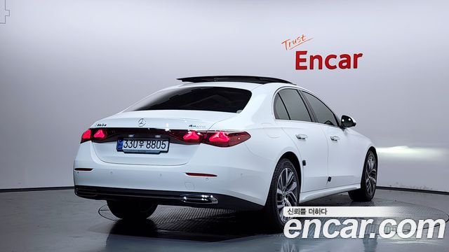 Крупный план задней части Mercedes E‑Class 2024, белый кузов, задние фонари и номерная табличка на повороте под углом три четверти.
