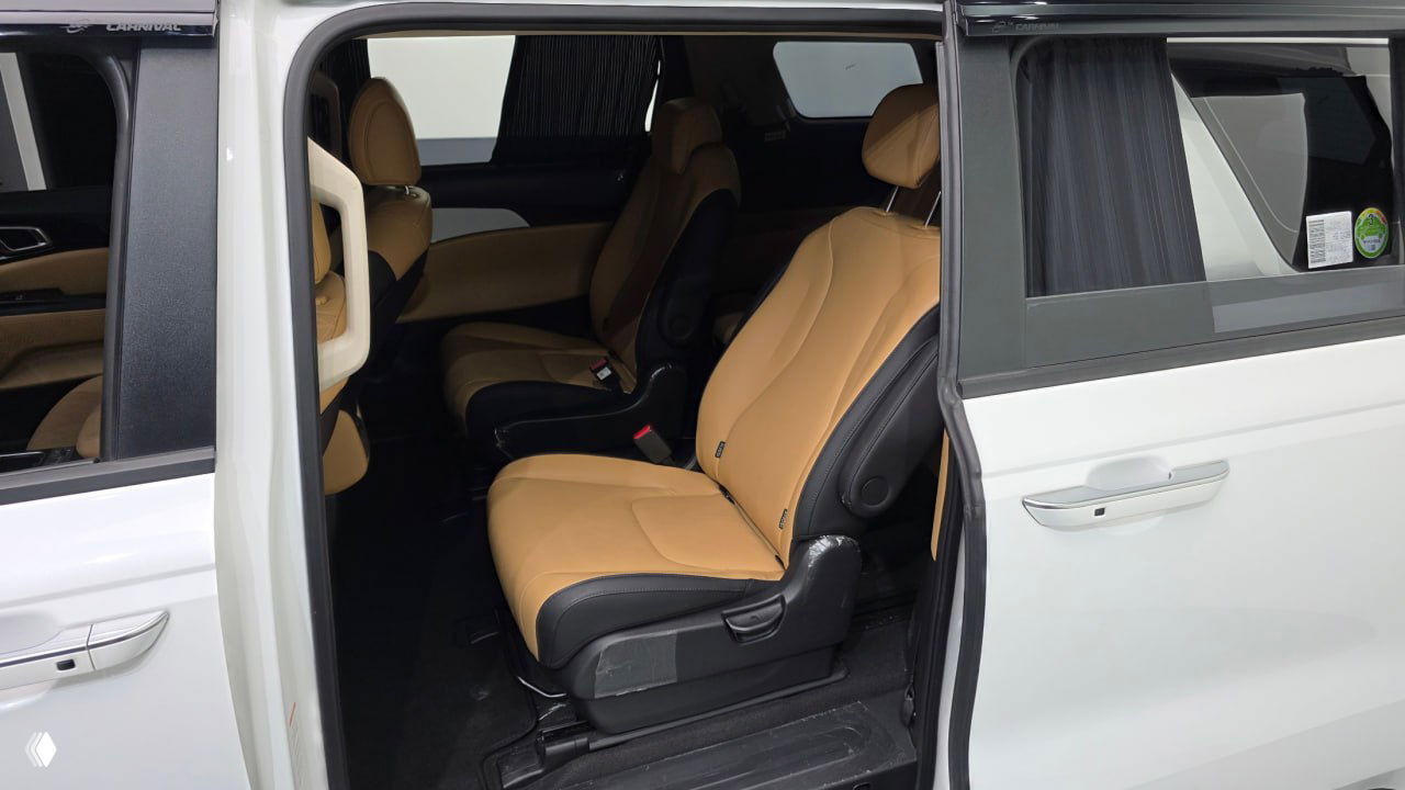 Средний ряд сидений Kia Carnival 9‑местного минивэна: раздвижная боковая дверь открыта, бежевые кресла и пространство для пассажиров хорошо видны.