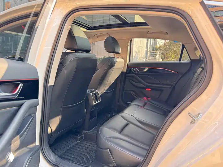 Задний ряд Bestune B70: тёмная кожаная обивка, пространство для ног и дверные панели — вид на пассажирский отсек с открытой дверью.