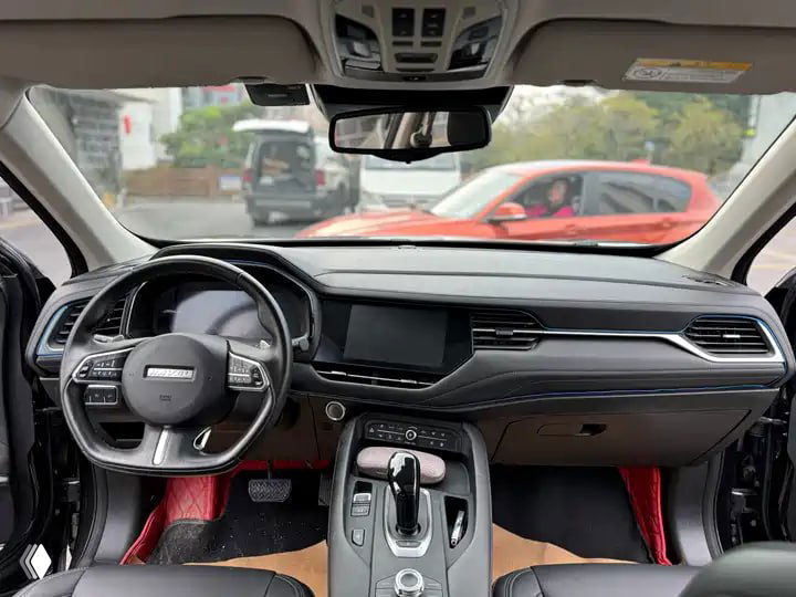Салон Haval F7: панель приборов, мультимедиа-экран и руль, вид на центральную консоль с селектором коробки и отделкой чёрно-красными вставками.