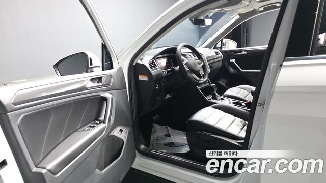 Салон Volkswagen Tiguan 2021 — передняя панель, руль и водительское кресло; интерьер в чёрной отделке, фото из объявления дилера Encar.