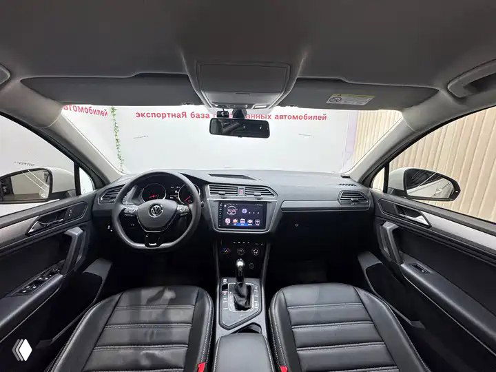 Интерьер Volkswagen Tiguan L: передняя панель, руль, мультимедиа-экран и кожаные сиденья — общий вид салона спереди.