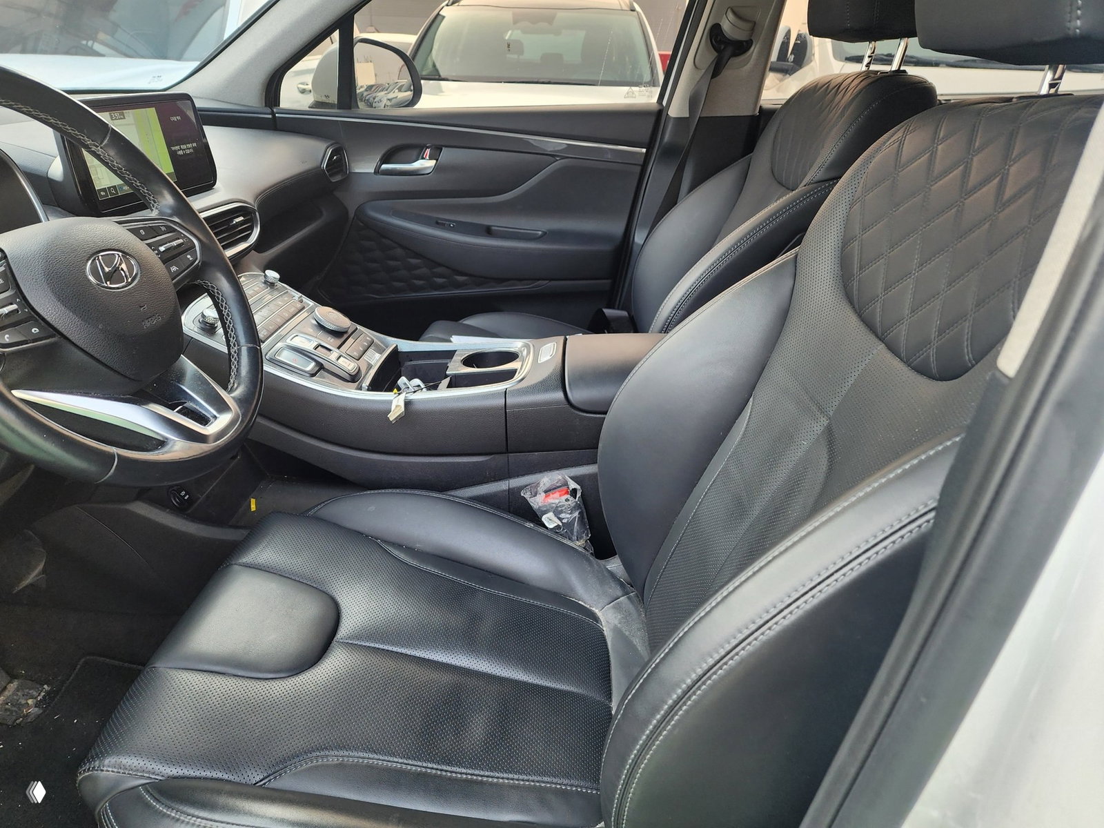 Интерьер Hyundai Santa Fe: передние чёрные кожаные сиденья, центральная консоль и руль, вид со стороны водителя, аккуратный салон без явных дефектов.