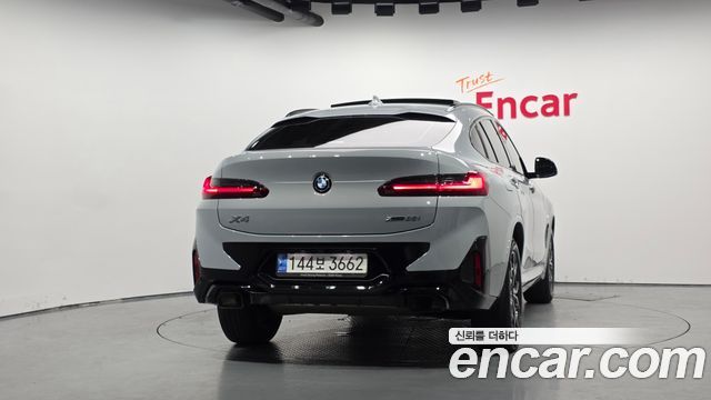 Вид сзади‑профиля BMW X4 xDrive20i M Sport 2022 в студии Encar — видно задние фонари, форму крыши и общую геометрию кузова для оценки внешнего состояния.