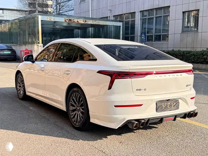 Вид сзади белого Bestune B70 на городской стоянке: кормовая часть автомобиля с LED-фонарями и легким антикрылом.