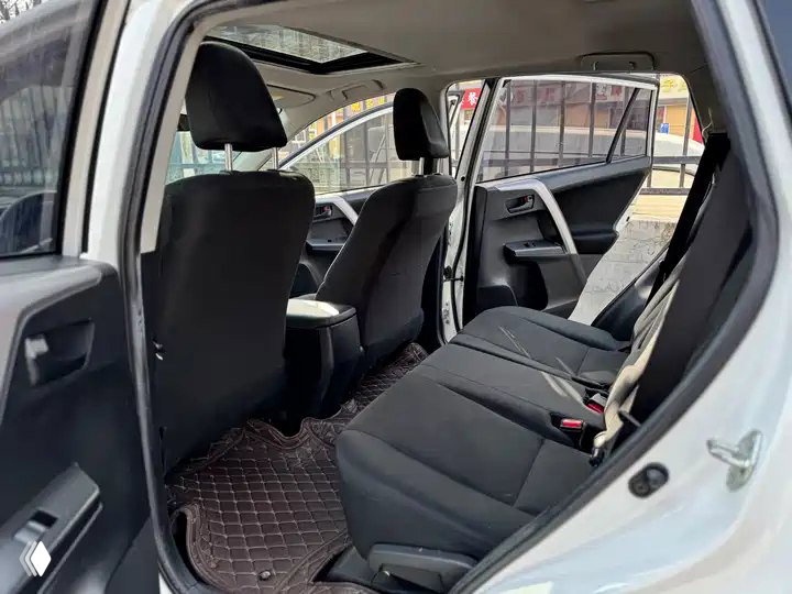 Задний ряд сидений Toyota RAV4 2019: тканевые кресла, пространство для ног и открытая дверь — общий вид задней части салона.