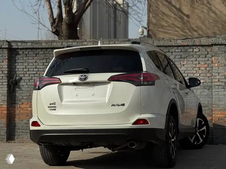 Вид сзади белого Toyota RAV4 2019: кормовая часть, фонари и бампер на парковке, отсутствует номерной знак на фото.