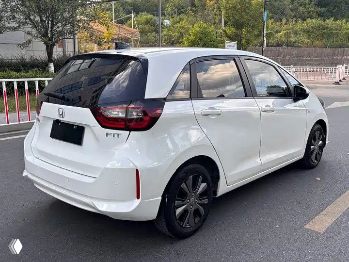 Белый Honda Fit 2022, вид сзади-полубоком на парковке; багажник и фонари хорошо видны, автомобиль подготовлен к отправке в РФ.