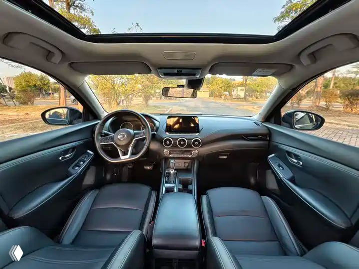 Салон NISSAN Sylphy 2023 с панорамной крышей, кожаными сиденьями и центральной консолью с мультимедиа — вид спереди через лобовое стекло.