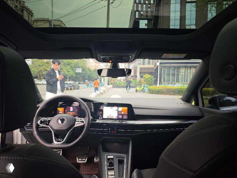 Интерьер Volkswagen Golf 2023: рулевое колесо, приборная панель, мультимедийный дисплей и панорамная крыша; внимание на оформление кокпита и посадку.