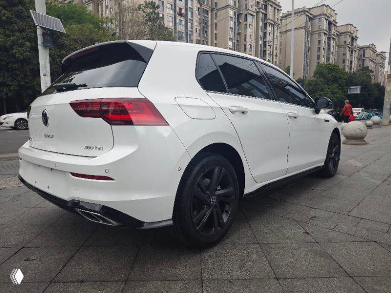 Белый Volkswagen Golf 2023 R-Line Lite, вид сзади слева на городской улице; видны задняя оптика, задний бампер, диски и общая линия кузова.