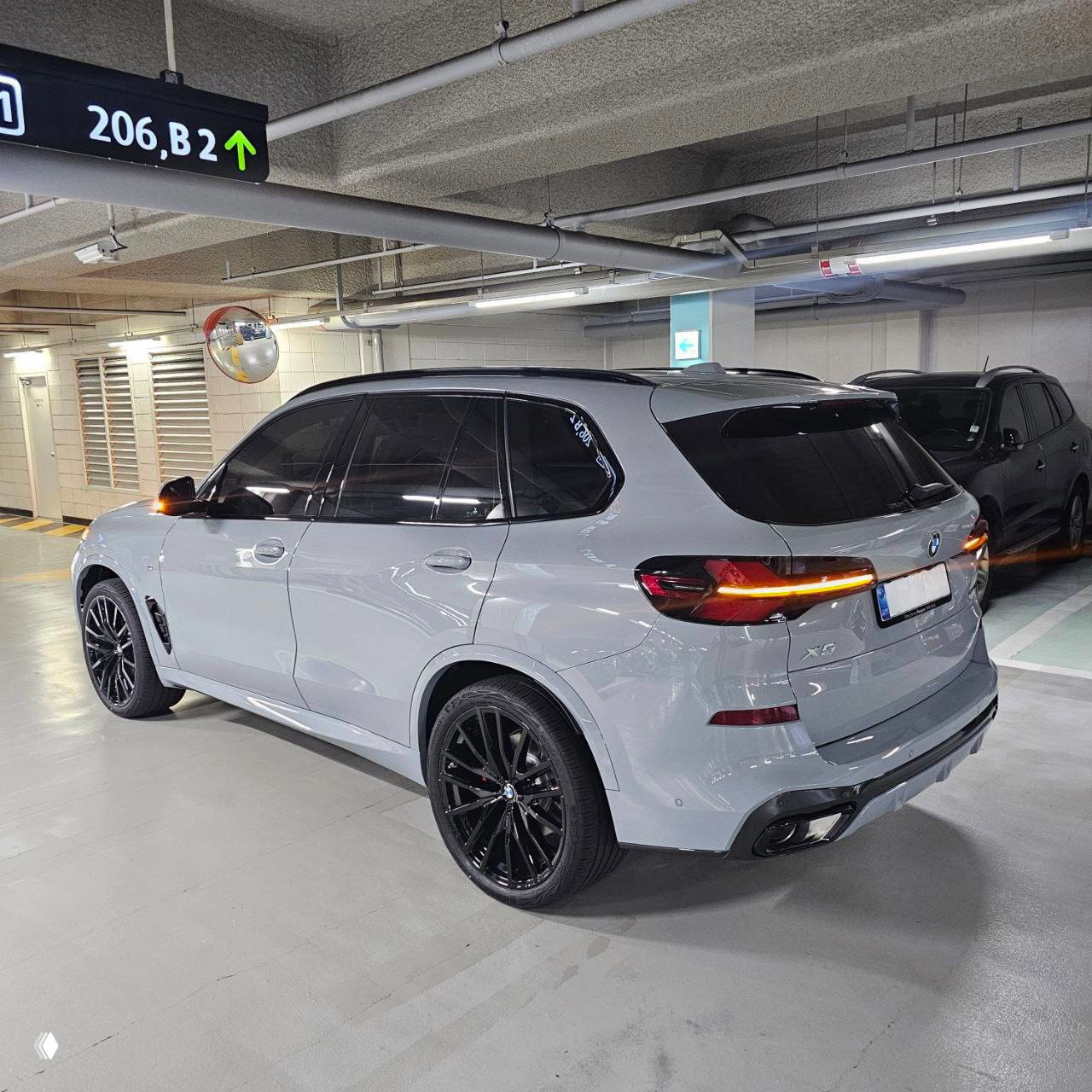 Задний трёхчетвертной вид BMW X5 xDrive40d 2026 на подземной парковке, видна задняя оптика, диффузор и тонированные стёкла.