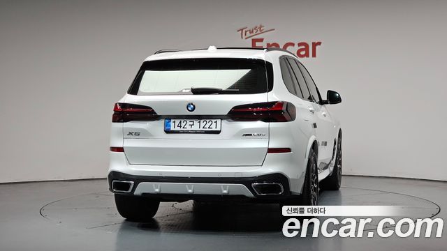 Белый BMW X5 xDrive 30d M Sport, вид сзади по центру в студии Encar; чётко видны задние фонари, бампер и выхлопные патрубки.