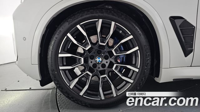 Крупный план легкосплавного диска и тормозной системы BMW X5 xDrive 30d M Sport с логотипом BMW и многоспицевым дизайном колеса.