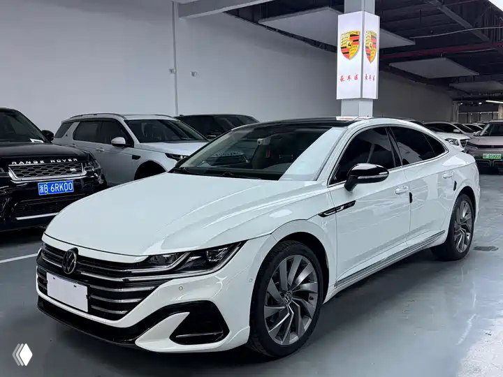 Белый седан FAW‑Volkswagen CC 2023 Striking Edition в автосалоне, вид спереди‑сбоку; видны фары, решётка и дизайн дисков и профиль кузова
